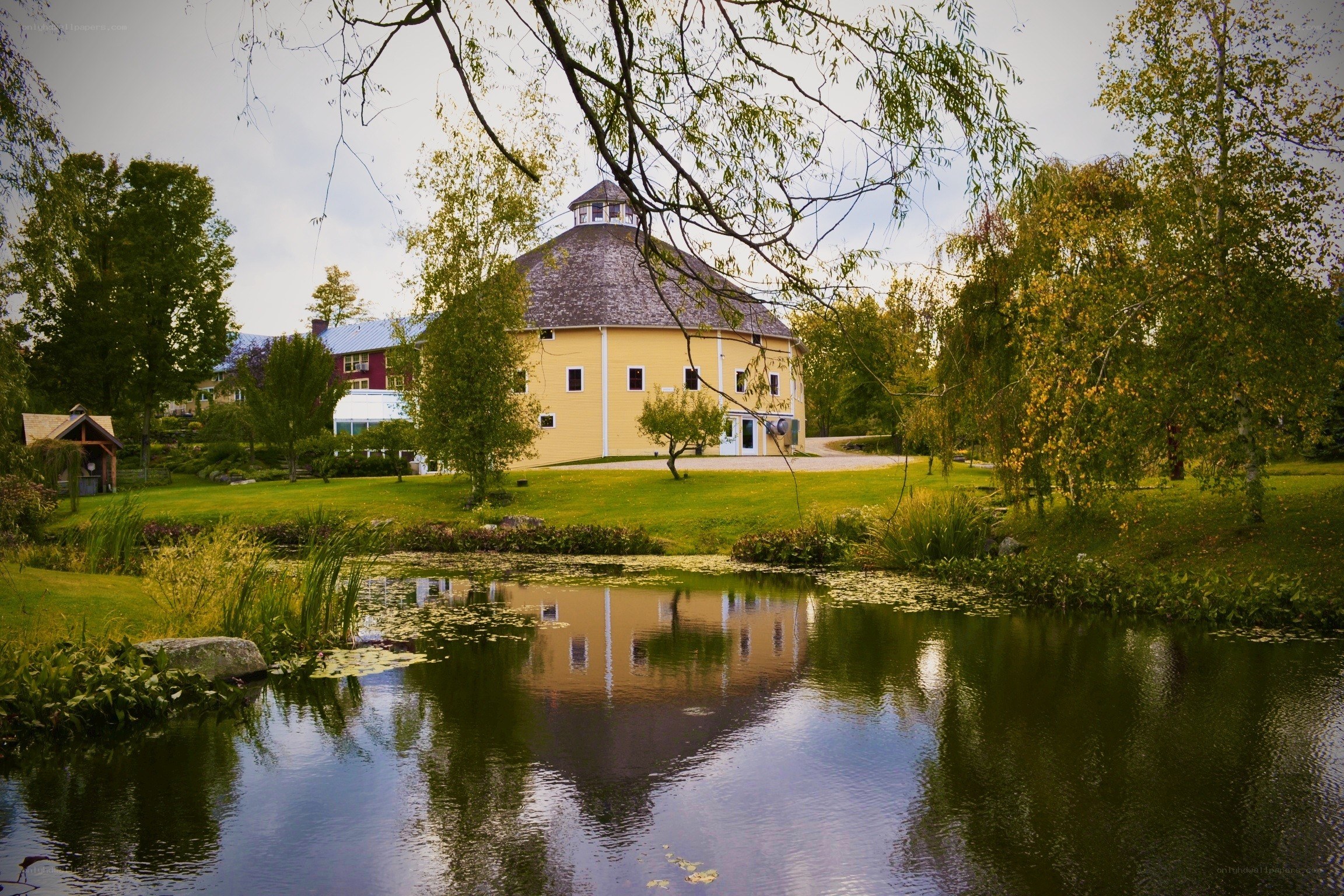 Round yellow barn by a pond