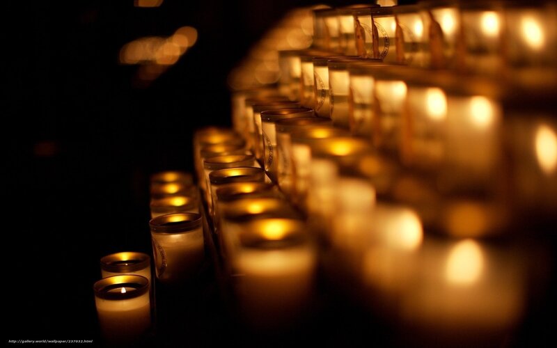 Rows of lit candles in darkness