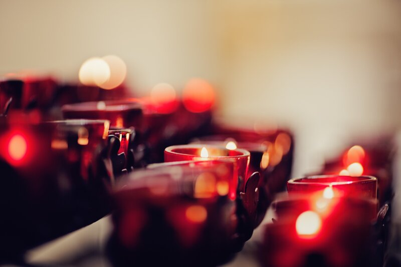 Rows of lit candles in red holders