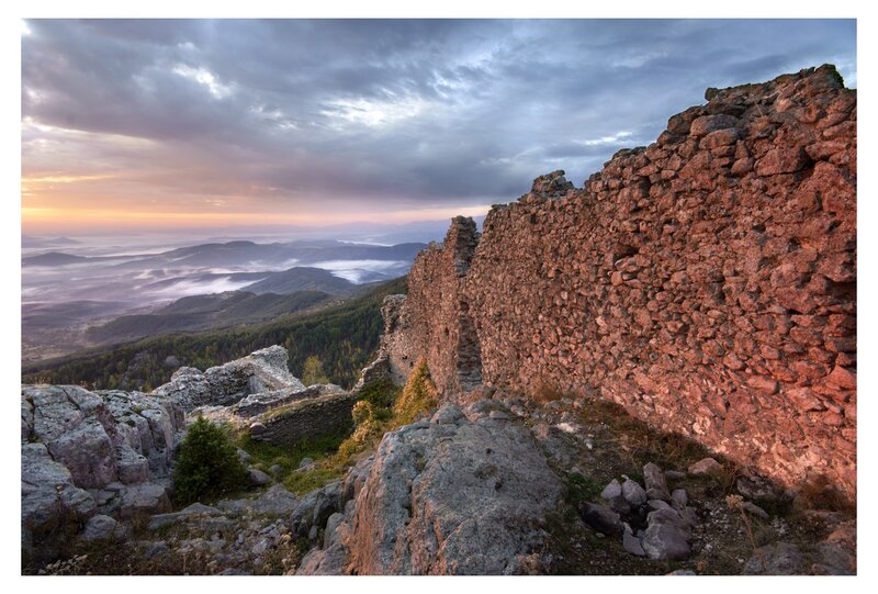Ruins at sunrise over misty valley
