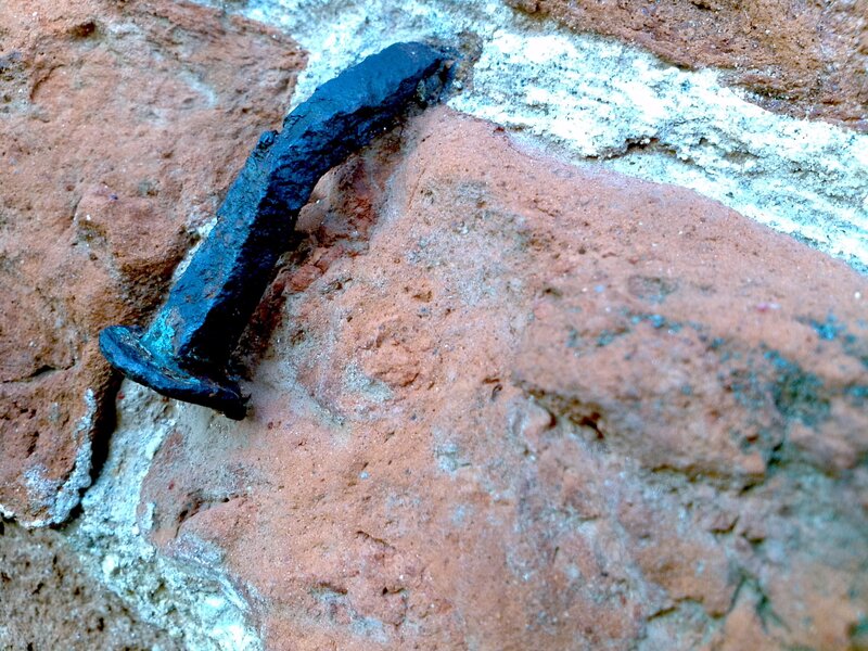 Rusted nail in brick wall