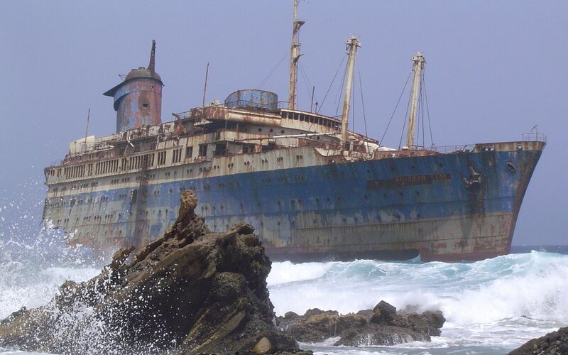 Rusted shipwreck on rocky shore