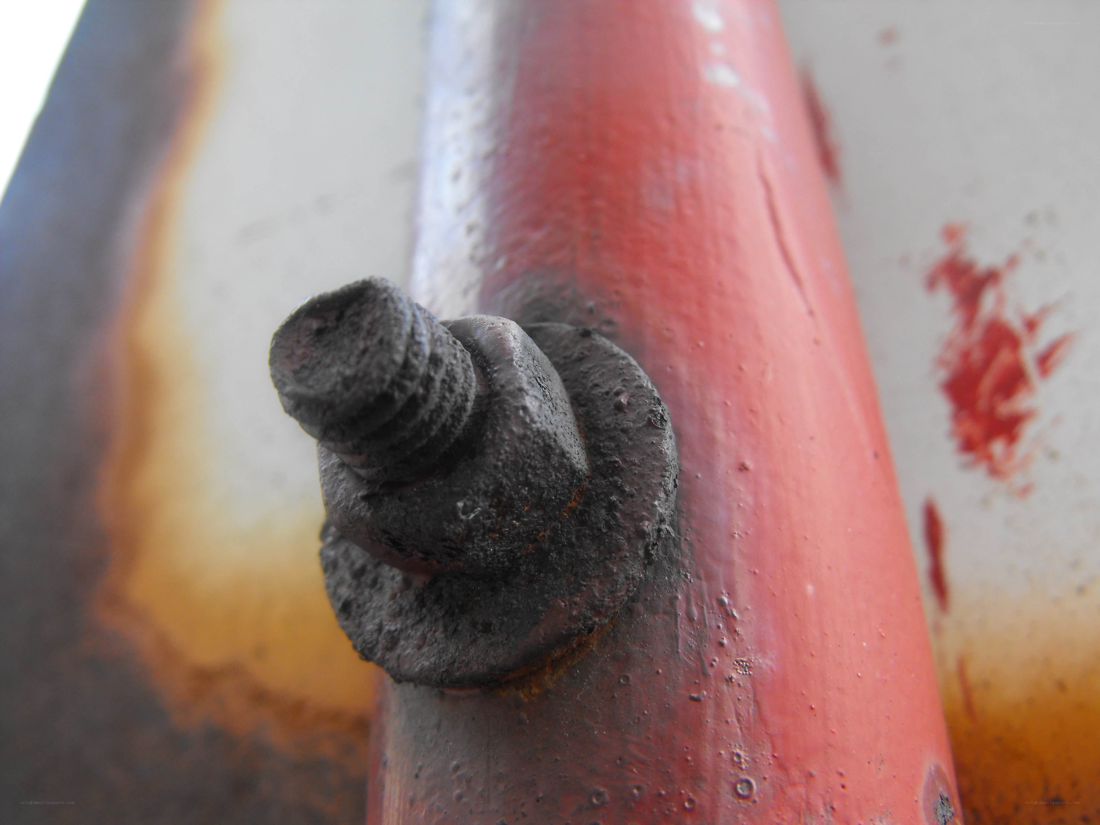 Rusty bolt on red pipe