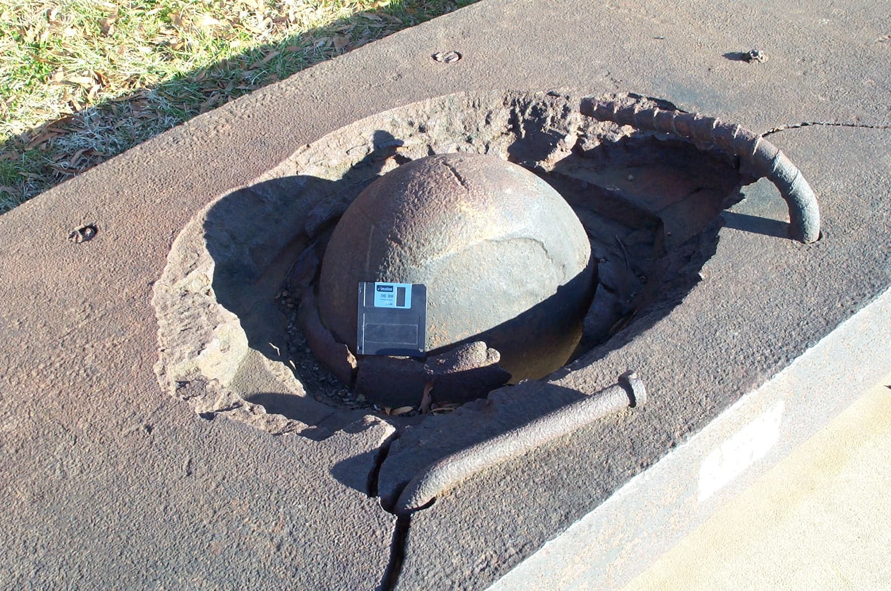Rusty cannonball in concrete