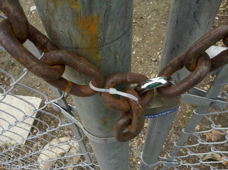 Rusty chain on metal fence