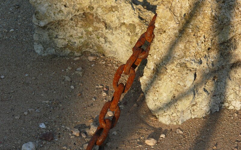 Rusty chain on rocky shore