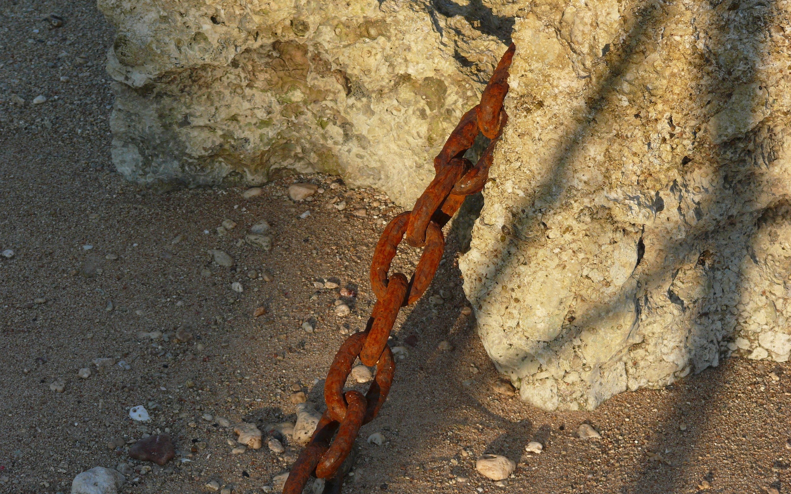 Rusty chain on rocky shore