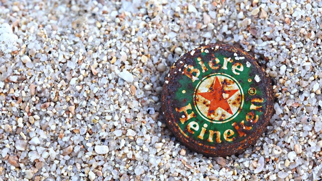 Rusty Heineken bottle cap on sand
