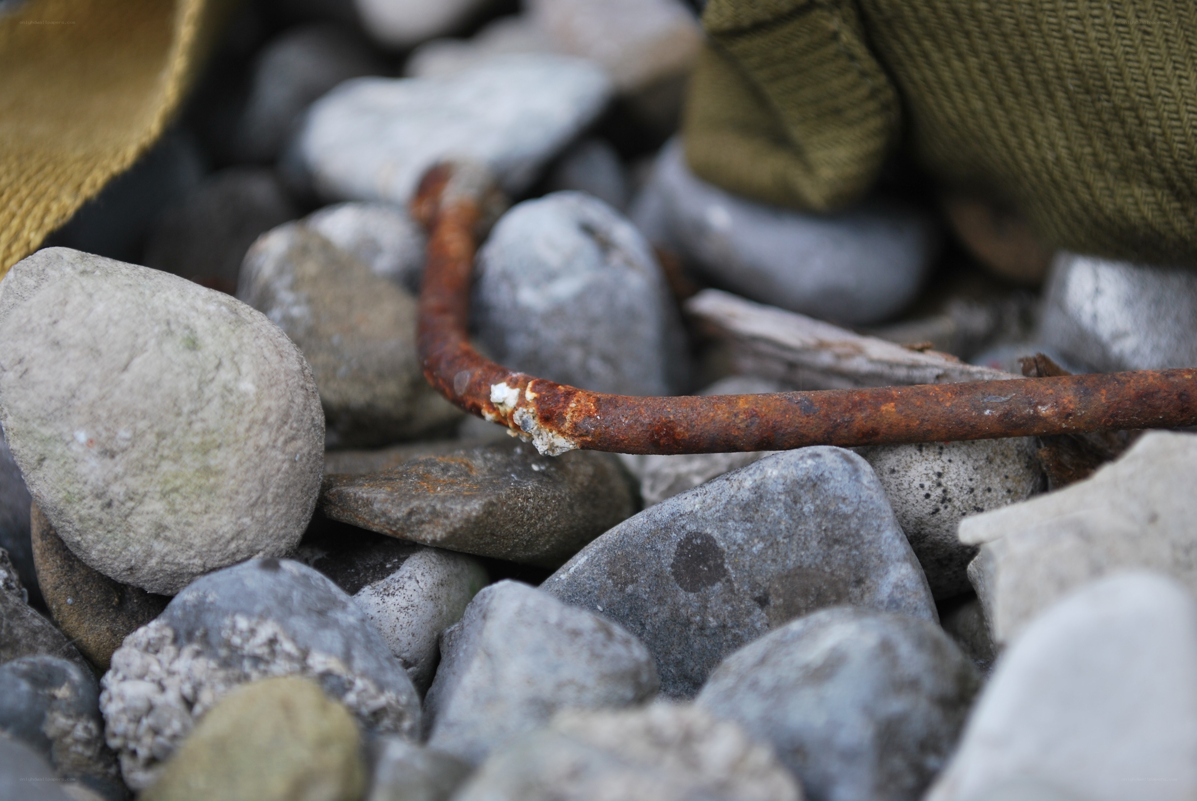 Rusty metal rod among pebbles