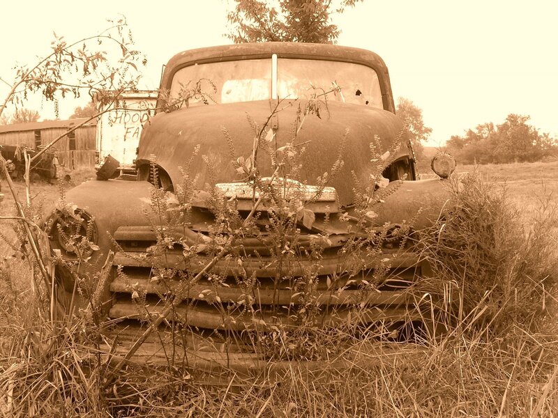 Rusty old truck in overgrown field