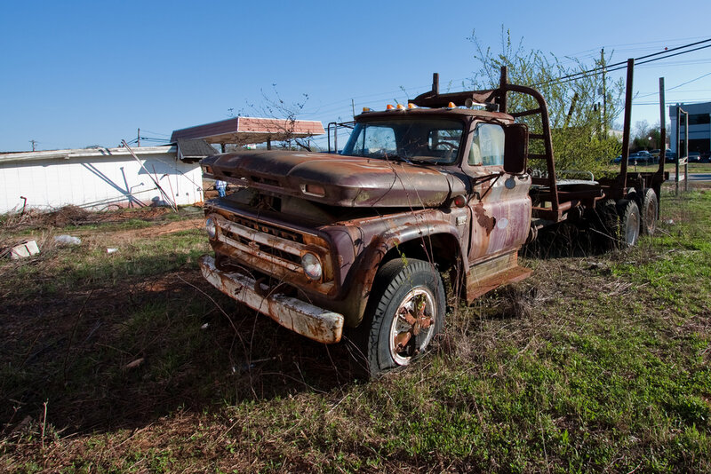 Rusty old truck in overgrown lot