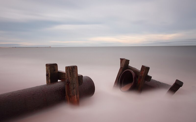 Rusty pipes on a misty beach