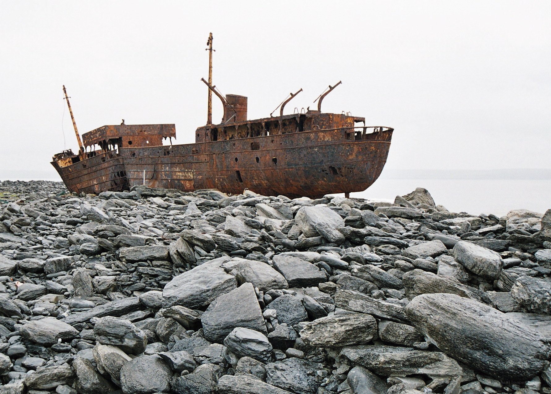 Rusty shipwreck on rocky shore