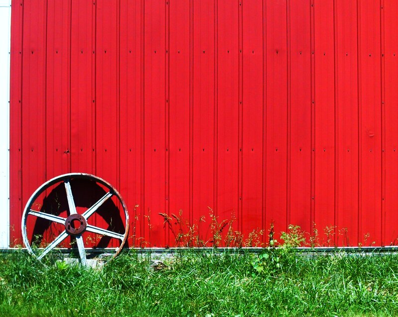 Rusty Wheel Against Red Wall
