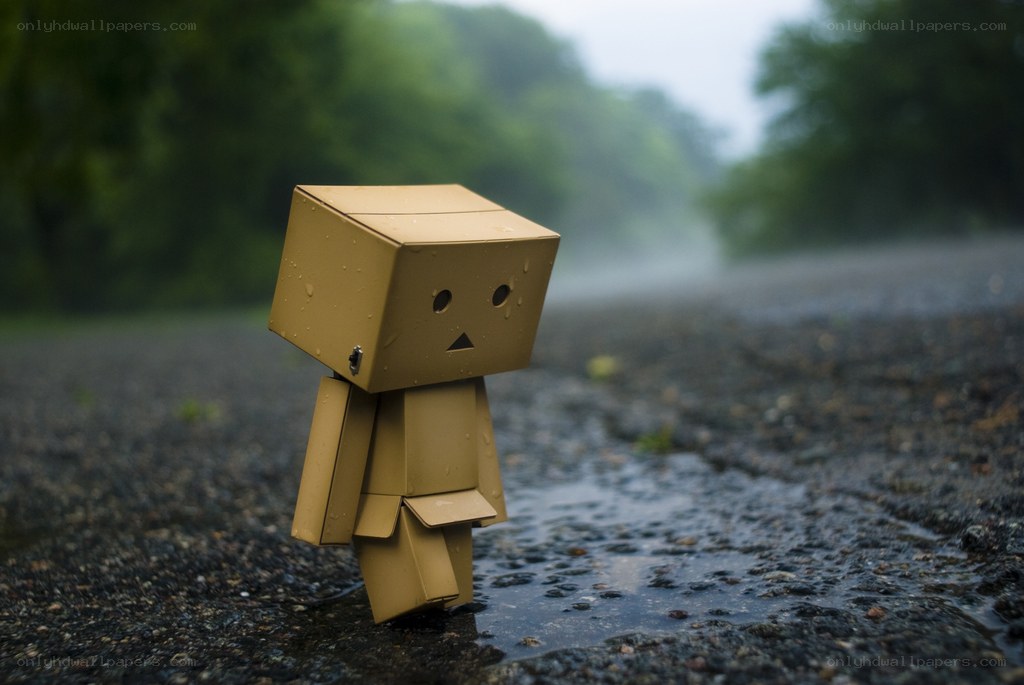 Sad cardboard robot in rain