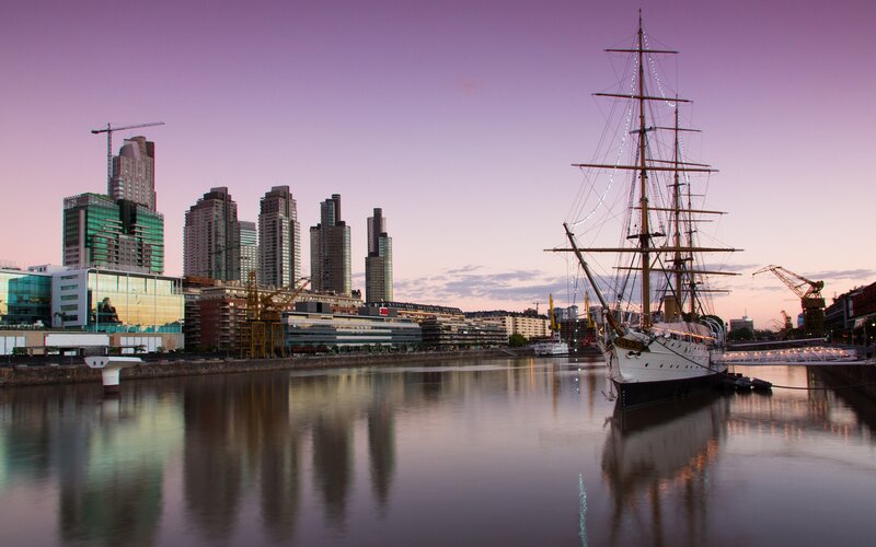 sailboat at dusk in city harbor