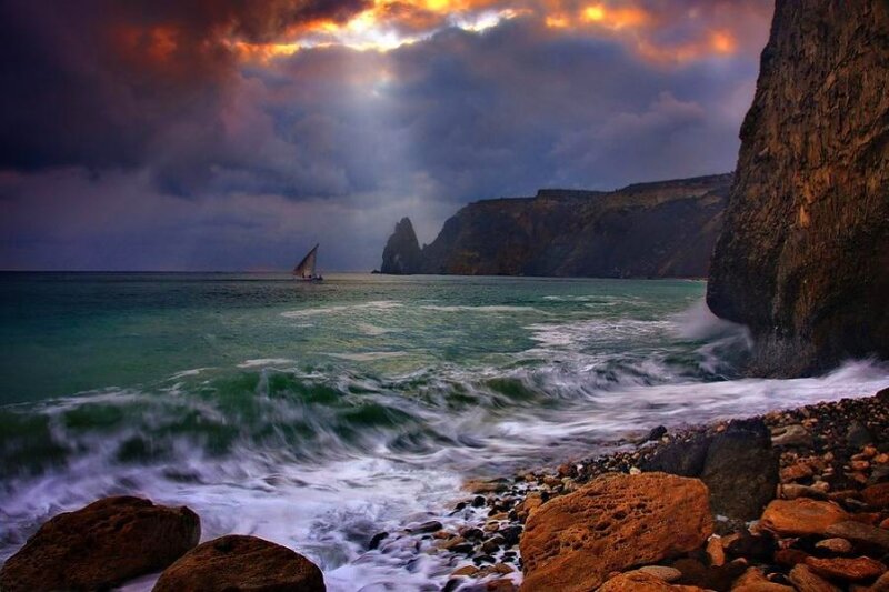 sailboat at rocky coastline