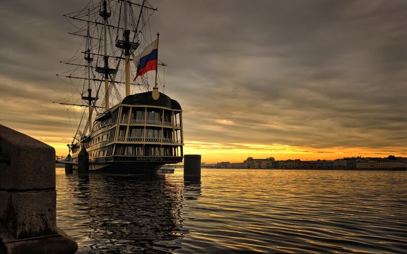 Sailboat at sunset in a city harbor