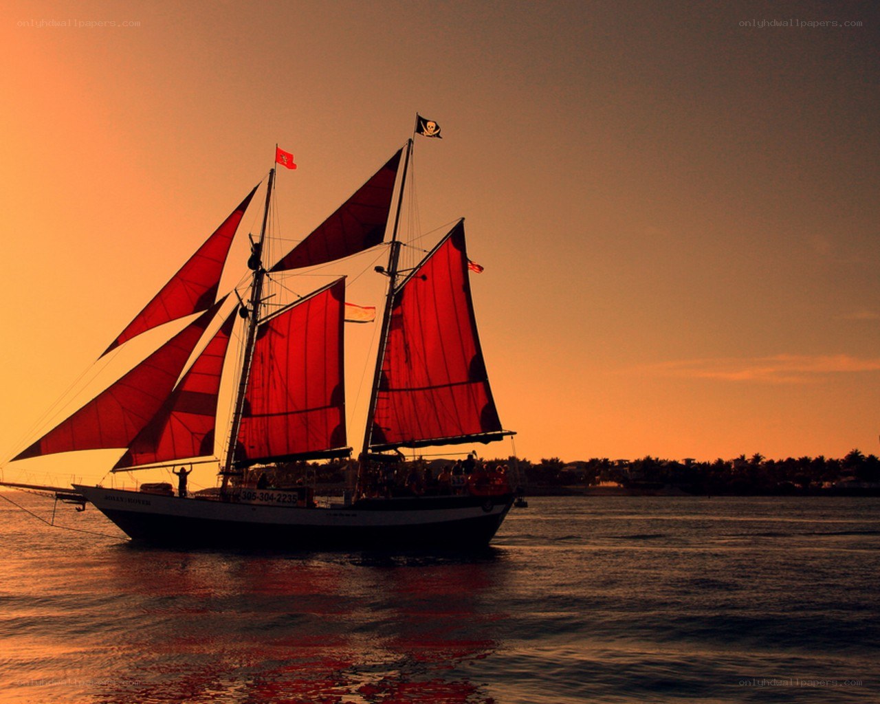 sailboat at sunset with red sails