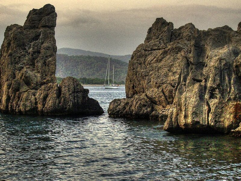 Sailboat between rocky cliffs