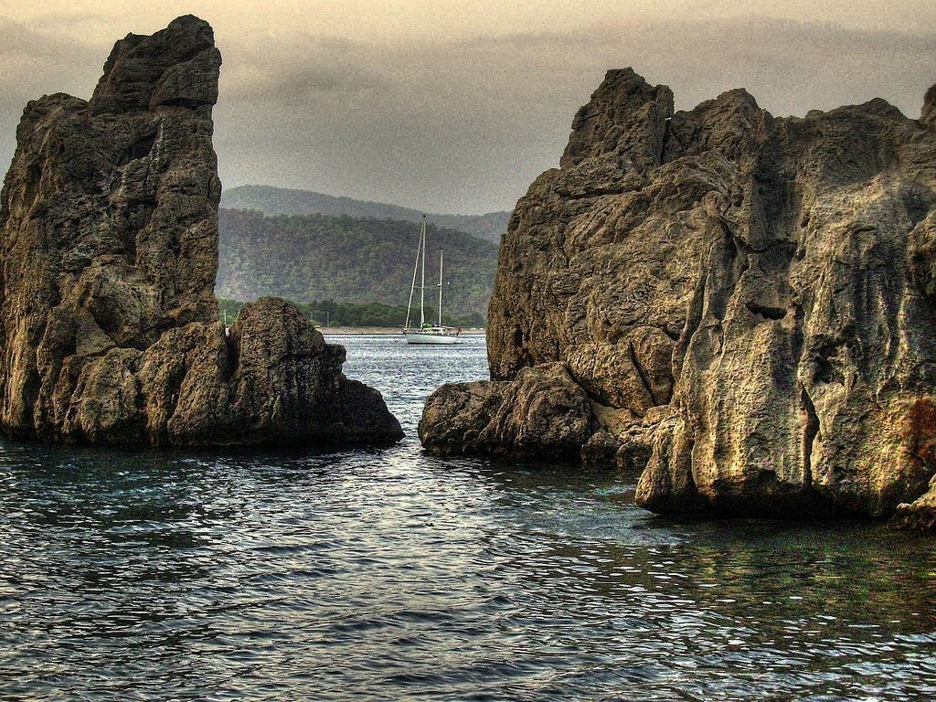 Sailboat between rocky cliffs
