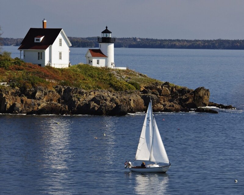 Sailboat near lighthouse on rocky coast