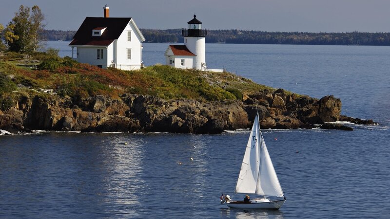 Sailboat near lighthouse on rocky coast