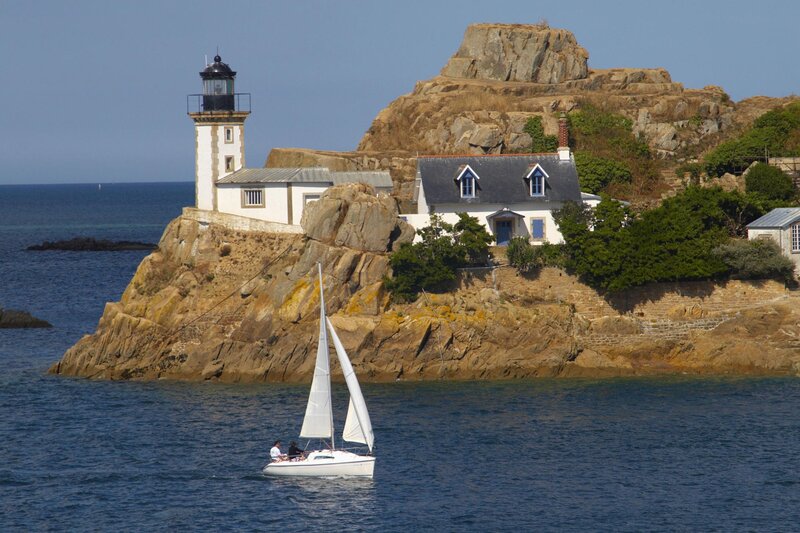 Sailboat near lighthouse on rocky island