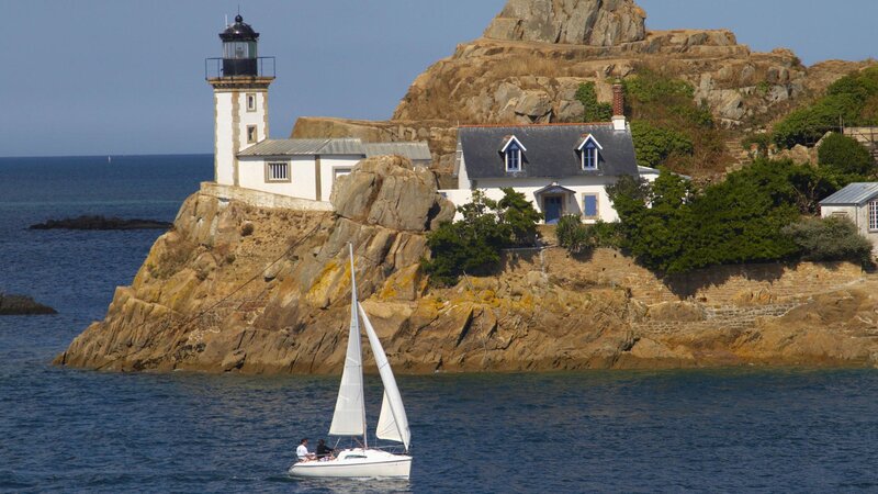 Sailboat near lighthouse on rocky island