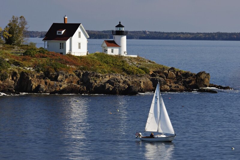 Sailboat near lighthouse on rocky shore