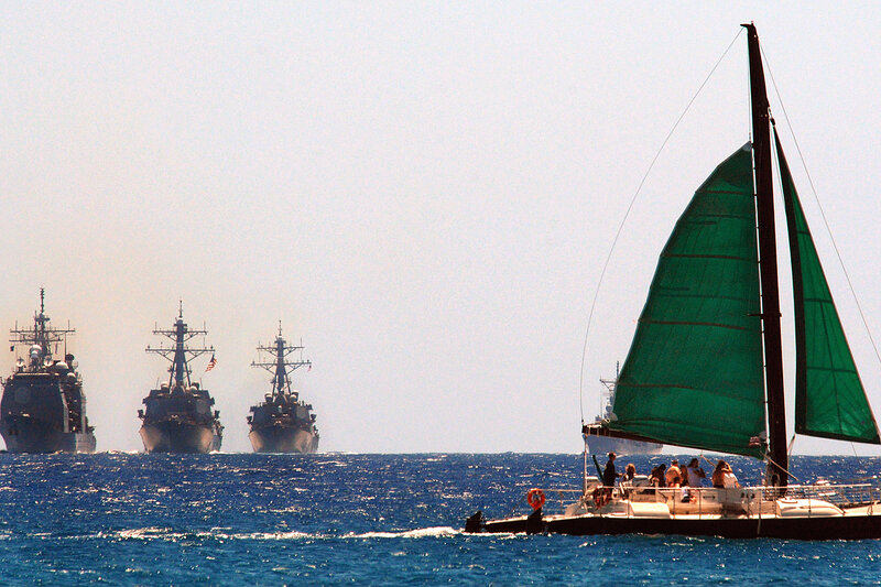 Sailboat near naval ships