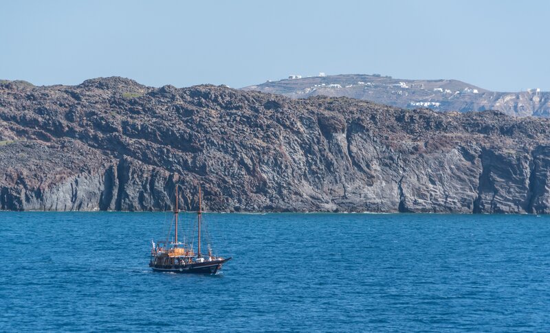 Sailboat near volcanic cliffs