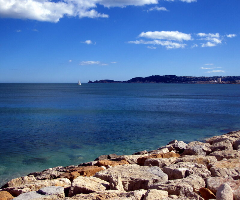 Sailboat on Calm Sea — Blue, Serene, Afternoon, Photograph, Rocks