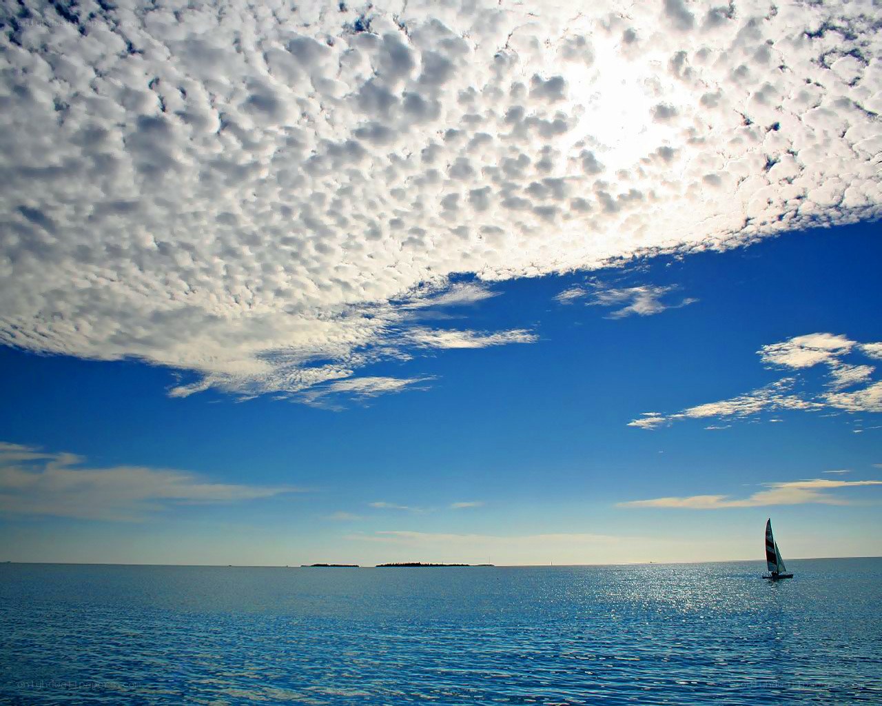 Sailboat on calm sea under cloudy sky