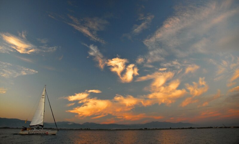 Sailboat on Calm Water — Blue, Serene, Sunset, Photograph, Clouds, Mountains