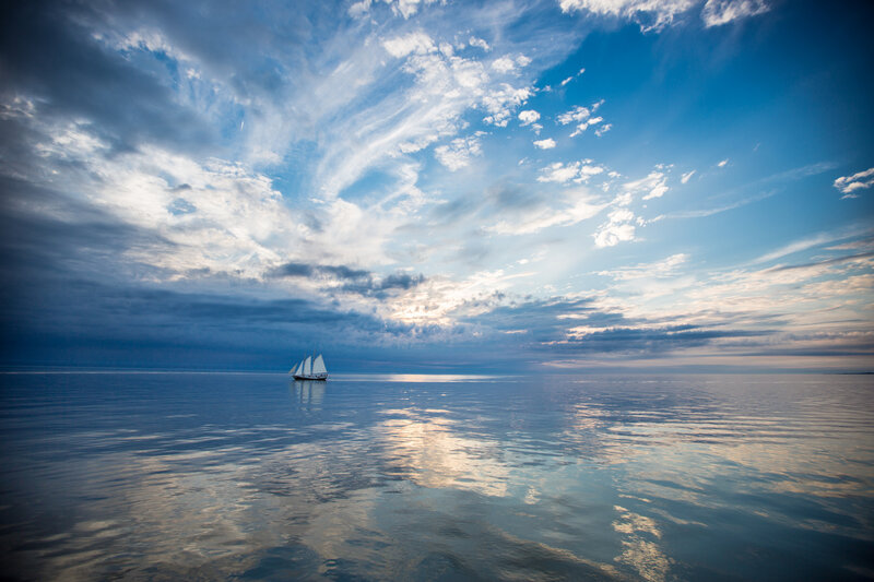 Sailboat on Calm Water — Blue, Serene, Sunset, Photograph, Clouds, Sky