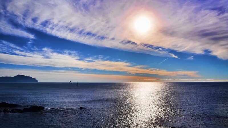 Sailboat on Ocean — Blue, Serene, Sunset, Photograph, Sun, Clouds, Island, White