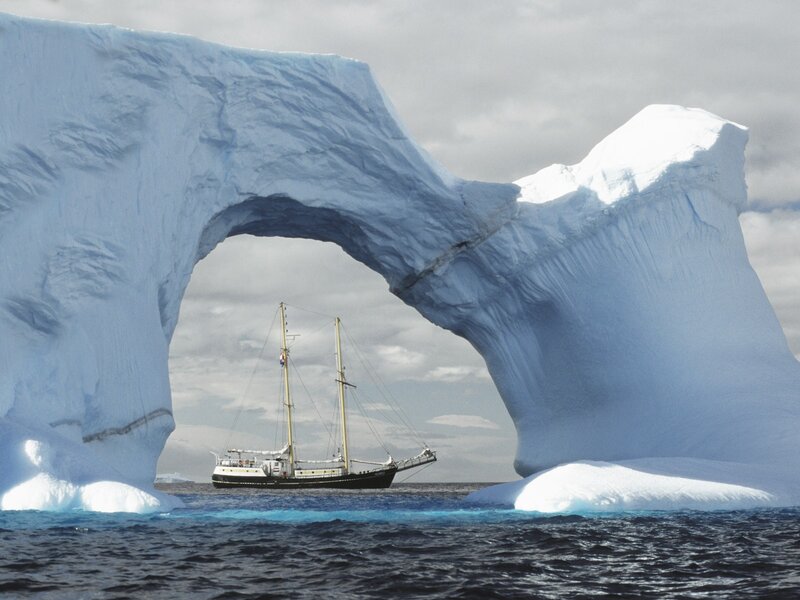 Sailboat under Iceberg Arch — Blue, Dramatic