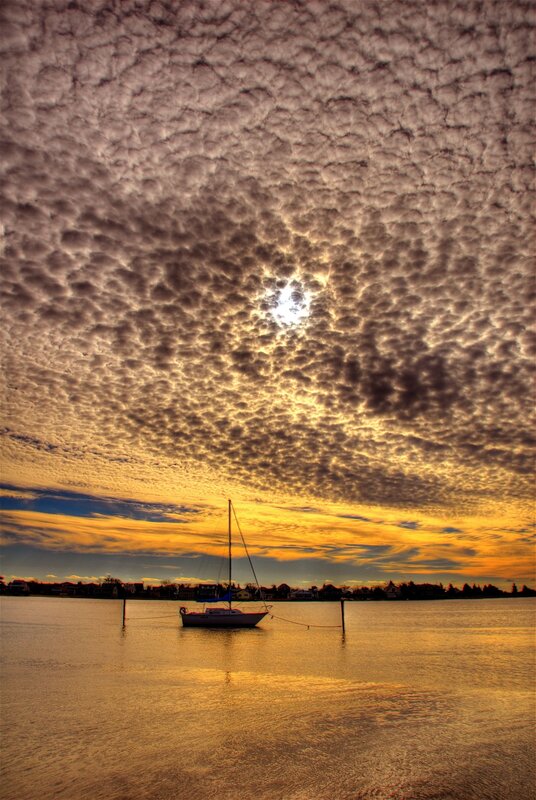 sailboat under textured clouds
