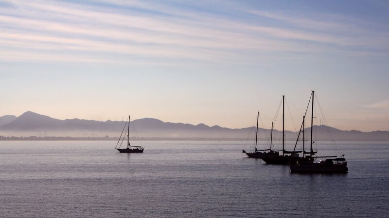 Sailboats at dawn on calm water
