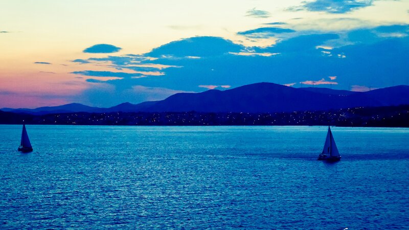 Sailboats at dusk on a calm sea