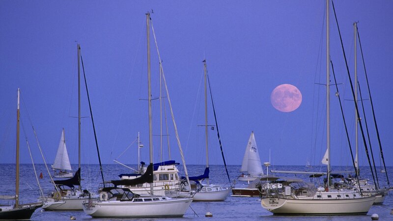 Sailboats at dusk with pink moon