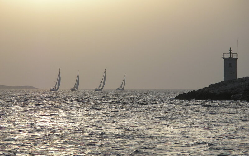 sailboats at sunset near lighthouse