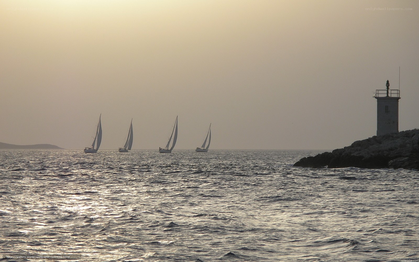 sailboats at sunset near lighthouse