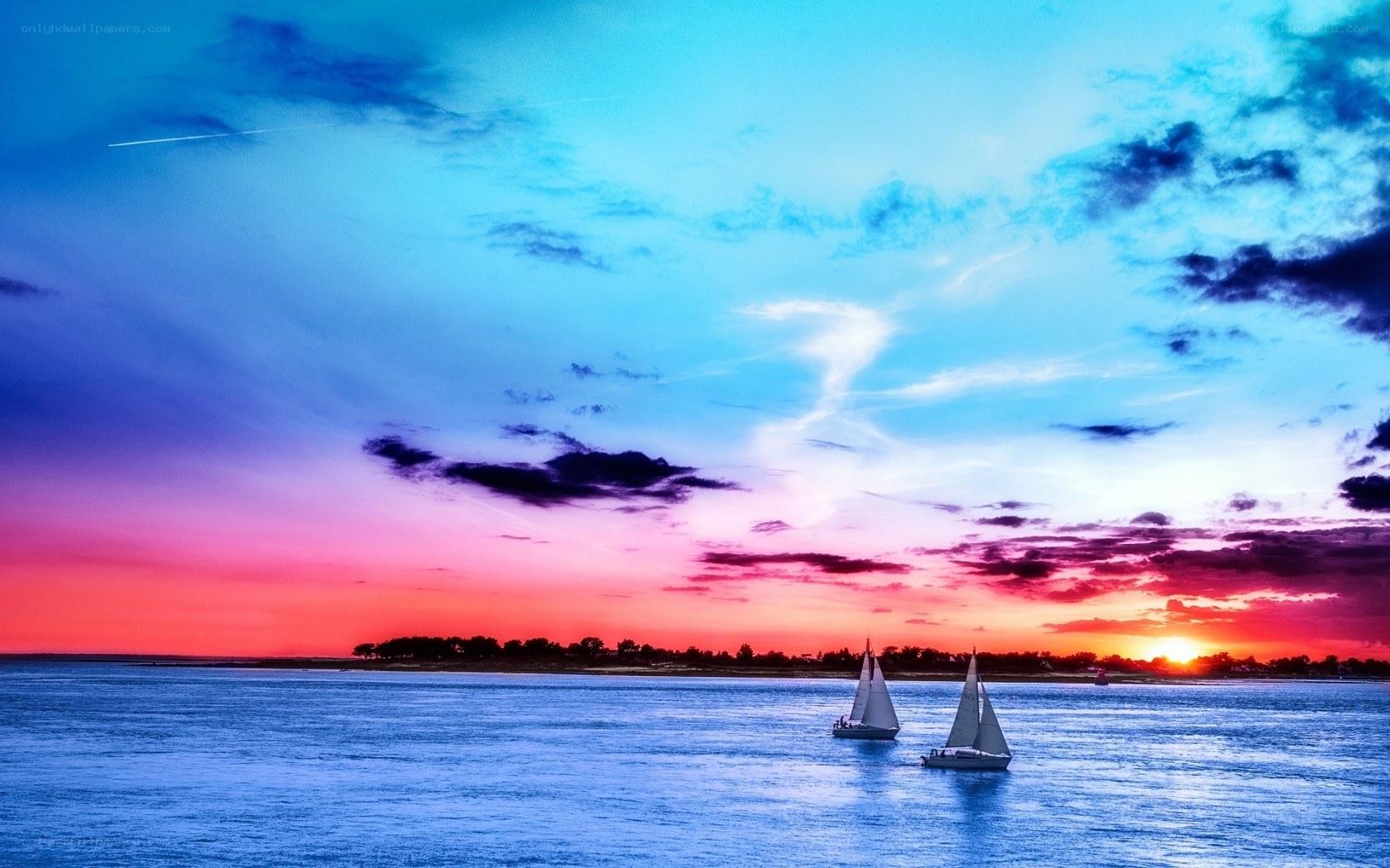 Sailboats at sunset over water