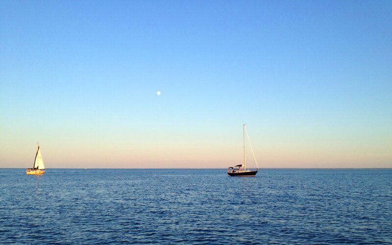 Sailboats on calm sea at dusk