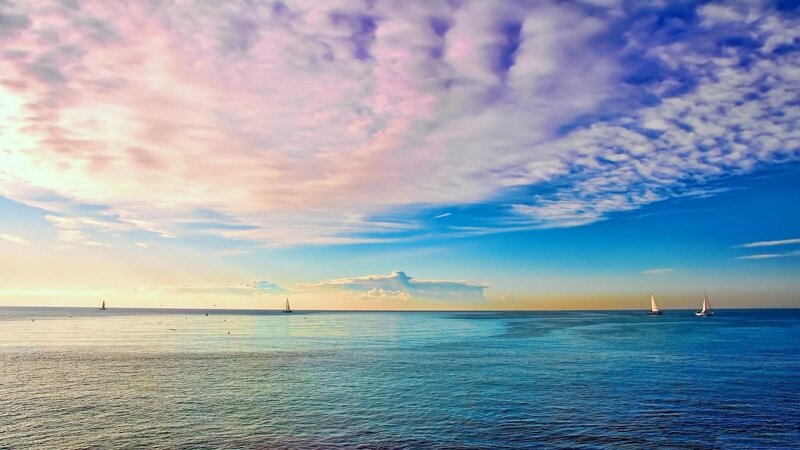 Sailboats on calm sea at sunset