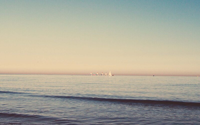 Sailboats on calm water at sunset