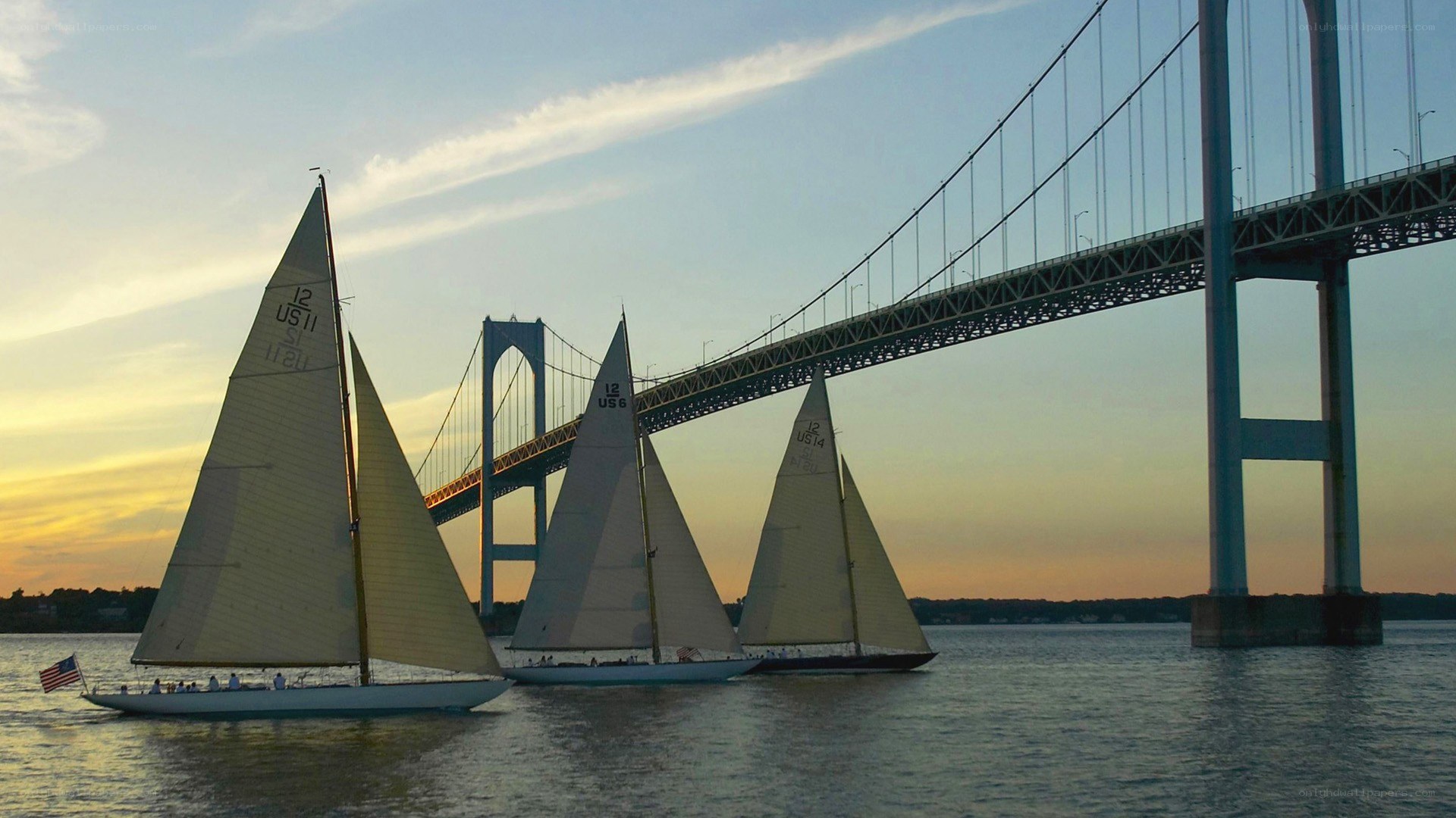 Sailboats under a bridge at sunset