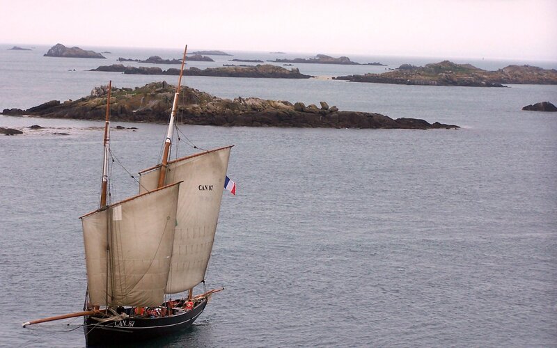 Sailing boat near rocky islands